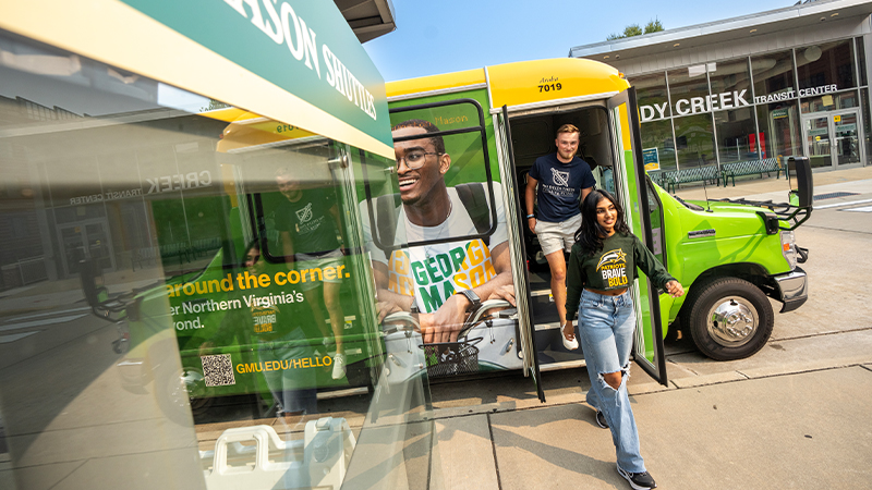 A pair of students exit a Mason shuttle onto the Fairfax Campus.