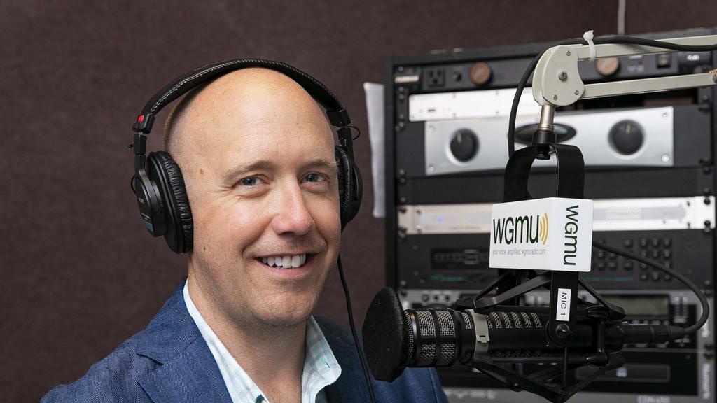 Jeremy Campbell speaks with President Washington on his podcast Access to Excellence. Jeffrey is a white male, bald head, wearing a blue suit jacket and unbuttoned collared shirt.